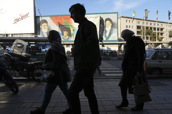 Pedestrians walk in front of a mural showing the late Iranian revolutionary founder Ayatollah Khomeini, in downtown Tehran on Saturday.