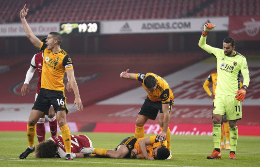 Players call for medical help after a head clash between Arsenal's David Luiz and Raul Jimenez of Wolves.