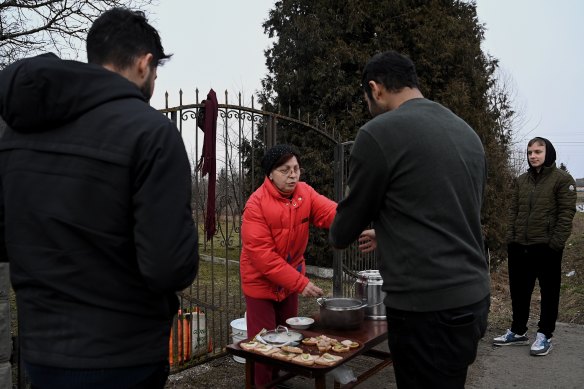 Oxana serves hot tea and sandwiches in front of her home to people heading to the Medyka crossing at the Ukrainian-Polish border.