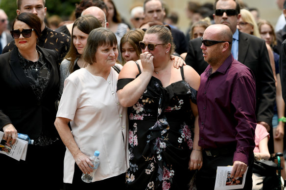 Mourners are seen embracing during a memorial service for White Island volcano victims Anthony, Elizabeth and Winona Langford at Maris College North Shore Auditorium in Sydney.