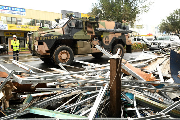 An army vehicle drives past debris in the flood-affected city centre of Lismore, NSW, in March.