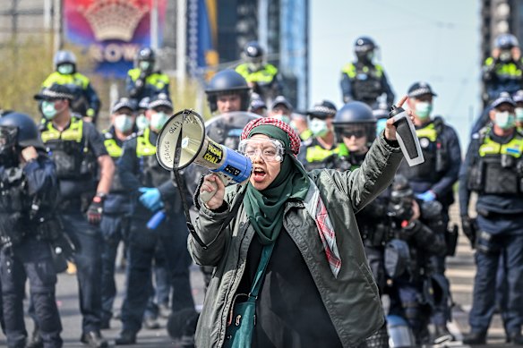 A protester leads anti-war chants in front of a line of police.