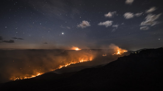 The Ruined Castle Fire burns under strong westerly winds in front of Mount Solitary at Echo Point in Katoomba.