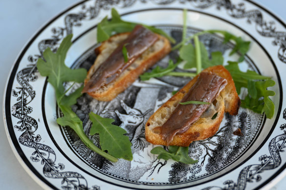 Thin slices of toasted baguette ferry anchovy fillets.