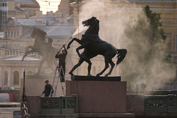 An employee of the Museum of Urban Sculpture cleans one of the four famous horse sculptures of the Anichkov Bridge over the Fontanka River in St. Petersburg, Russia.
