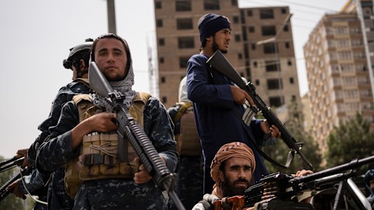 Taliban fighters escort women march in support of the Taliban government outside Kabul University on September 11.