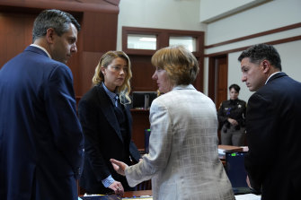 Actor Amber Heard speaks to her legal team during a lunch break.