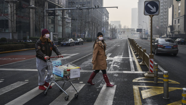 A couple cross the road in a deserved Beijing. The coronavirus has hit demand for products from Australian companies in their key export market. 