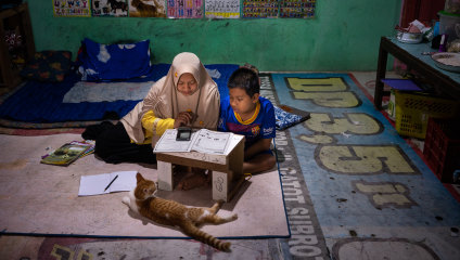Syaiful, 12, who can’t freely move his lower body or right hand, studies at home with his mother Nurhidayah in Banyumas, Central Java.