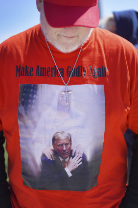 A supporter of Donald Trump attends a rally wearing a shirt that reads: “Make America Godly Again”.