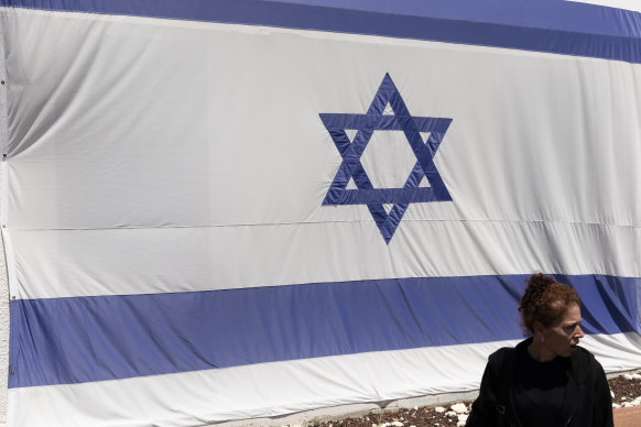 A woman walks by an Israeli flag amid fears of Iran attack after it blamed Israel for a strike on its consulate in Syria.