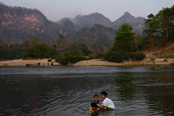 A woman and children bathe on the Thai side of the Moei River border.