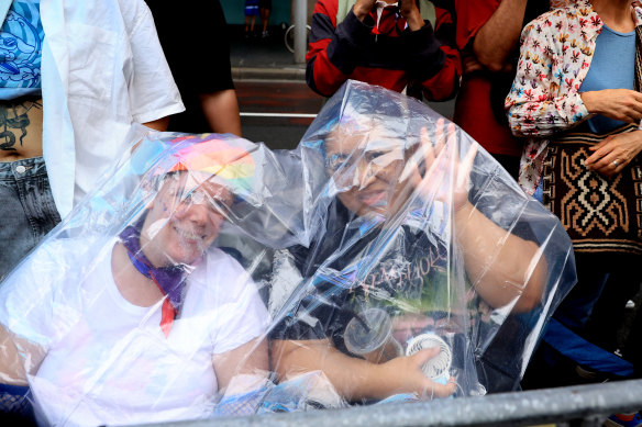 Spectators shelter under a poncho. 