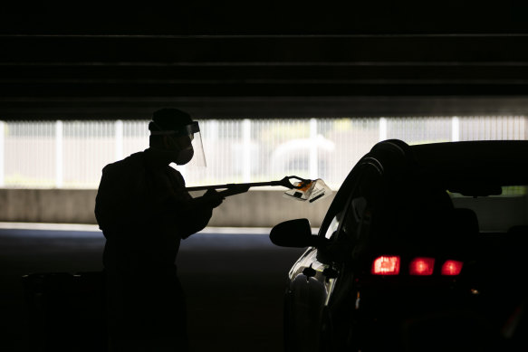 A healthcare worker uses a grabber to collect a nasal swab sample at a COVID-19 drive-through testing site in California.