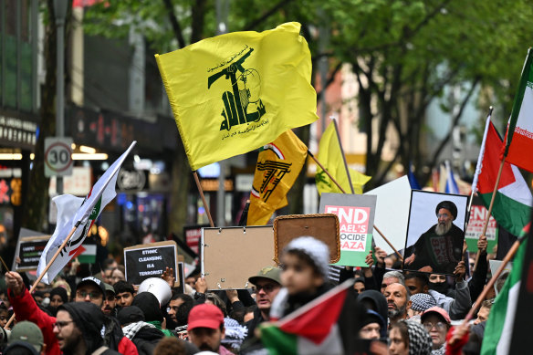 Protesters raise the flag of Hezbollah, a proscribed terrorist group, outside the State Library of Victoria.