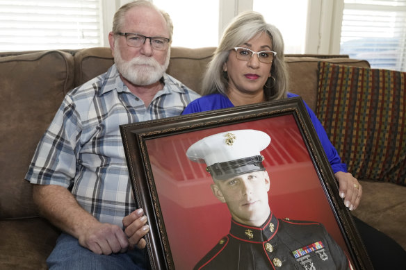 Joey and Paula Reed pose for a photo with a portrait of their son Marine veteran and Russian prisoner Trevor Reed at their home in Fort Worth, Texas.