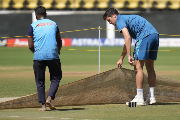 Australian captain Pat Cummins removes the cover to inspect the pitch ahead of the first cricket in Nagpur, India. 