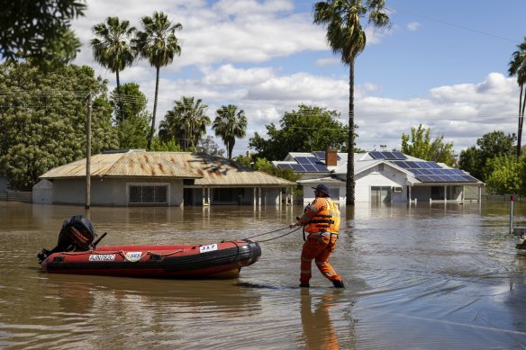 Emergency crews transport people by boat over flooded streets in Forbes.