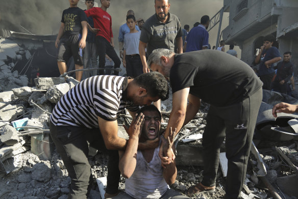 Palestinians comfort a crying man after losing relatives under the rubble of a destroyed house following an Israeli airstrike in Gaza City,