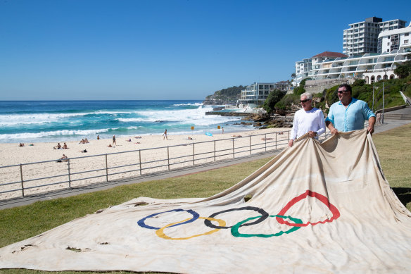 John Whitehead and David Hynes with the Olympic flag at Bondi Beach.