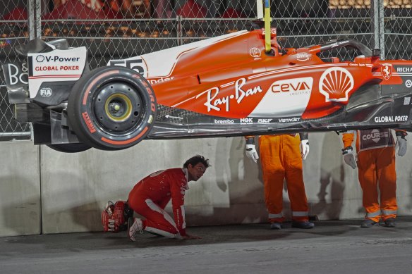 Carlos Sainz inspects the underbelly of his car after running over the manhole.