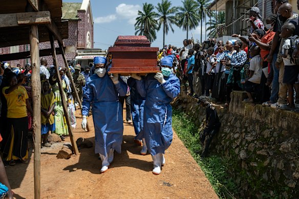 Health workers carry a coffin with the body of Reverend Sylvestre Atama.