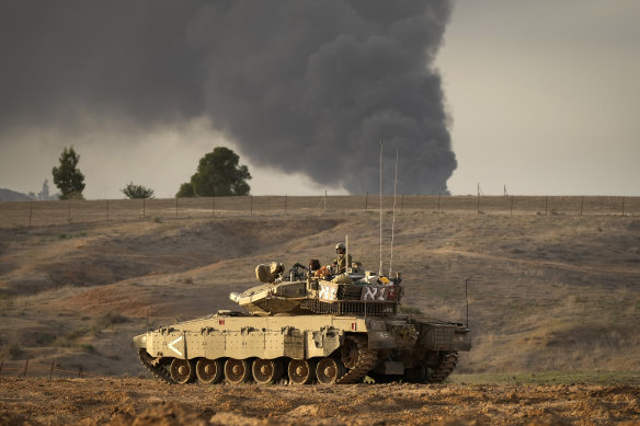Smoke from Gaza City fills the sky in the distance as an Israeli tank heads towards the Gaza strip.
