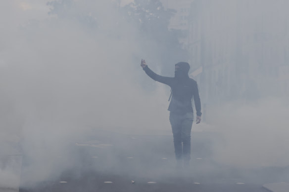 Cumartesi günü Fransa'nın batısındaki Nantes kentinde düzenlenen bir gösteri sırasında bir protestocu göz yaşartıcı gaz bulutunun içinden geçerken el hareketi yapıyor.
