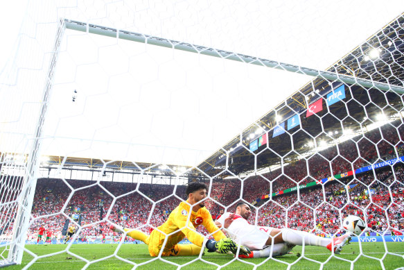 Mehmet Zeki Celik and Altay Bayindir of Turkiye attempt to clear the ball from the goal-line.