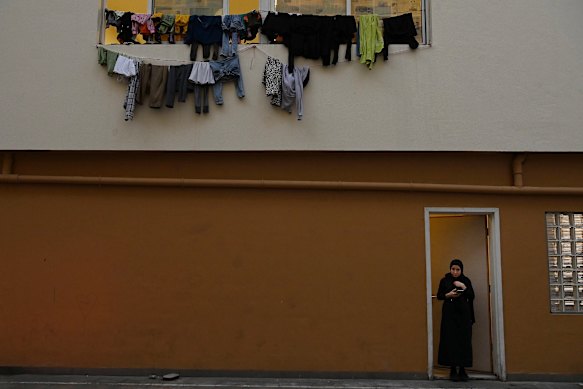 A woman staying at the al Zarif Intermediate School stands under washing hanging from the windows. 