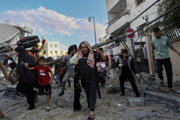 Palestinian families rush out of their homes after Israeli airstrikes targeting their neighbourhood on Tuesday.