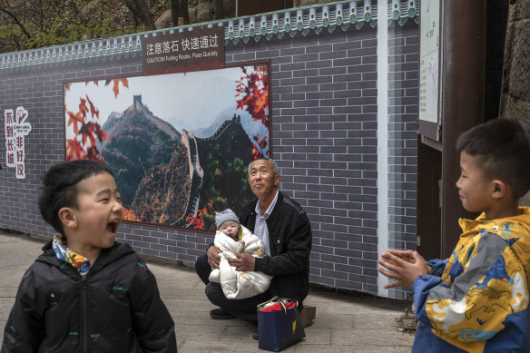 Çin Seddi'nde bir adam diğer akrabalarının yanında bir bebeği kucağında tutuyor.  Devlet ailelerin daha çok çocuk sahibi olmasını istiyor.