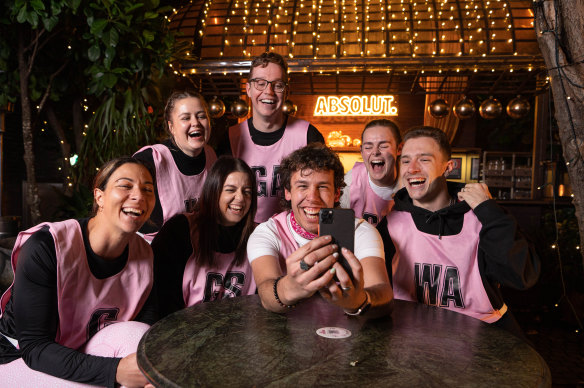 Jacob McIntyre (holding phone) is one of the thousands of men taking up netball, fuelling the sport’s growing popularity.