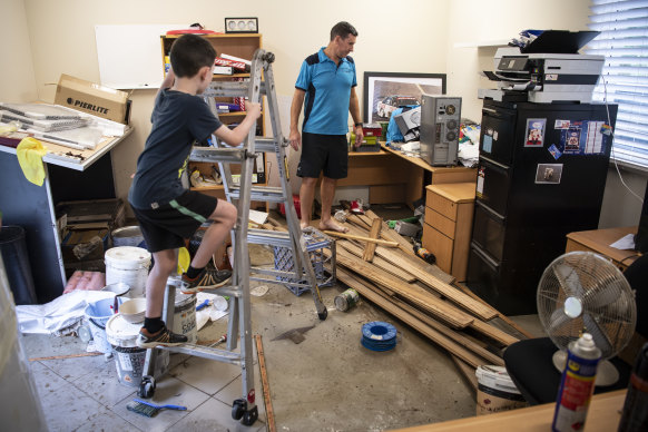 Jason Byrne with his son Liam in his flood damaged office in Penrith.