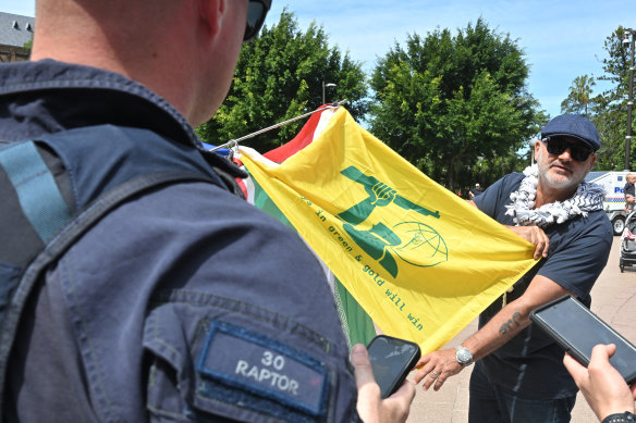 An image from the rally also shows a man, allegedly Yazbek, holding a flag with the words “our boys in green and gold will win”.