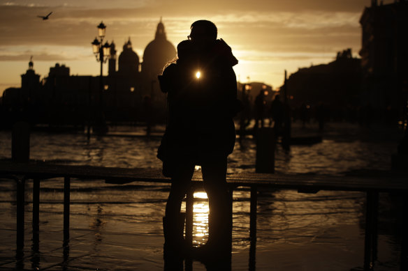 A couple watches the sun set over a flooded Venice following a 1.5-metre tide.