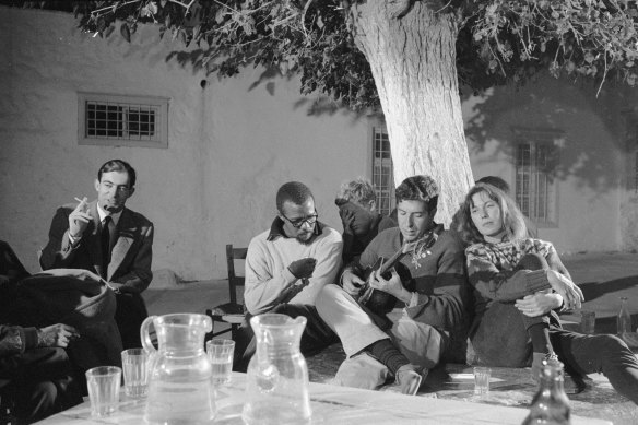 Charmian Clift and American poet Charles Heckstall listen as Leonard Cohen plays guitar in Hydra in October 1960.