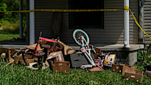 Police tape and debris are seen at a home where authorities say they removed 16 children and arrested four adults.