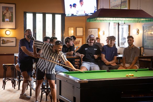 The pool table sits under a fringed lamp.