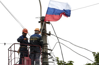 Municipal workers attach a Russian national flag to a pole preparing to celebrate 77 years of the victory in WWII in Mariupol,  Thursday, May 5, 2022.