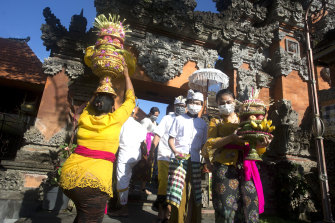 People wearing face masks as a precaution against coronavirus outbreak carry offerings during Hindu festival of Galungan in Bali, Indonesia.