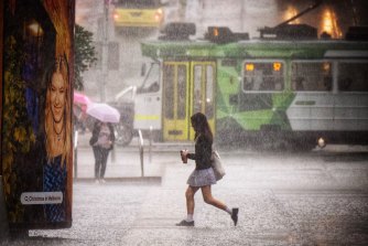 Pedestrians run for cover during a thunderstorm in Melbourne today.