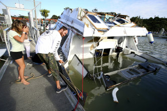 A couple look at a damaged boat in a marina at Tutukaka, New Zealand, on Sunday.