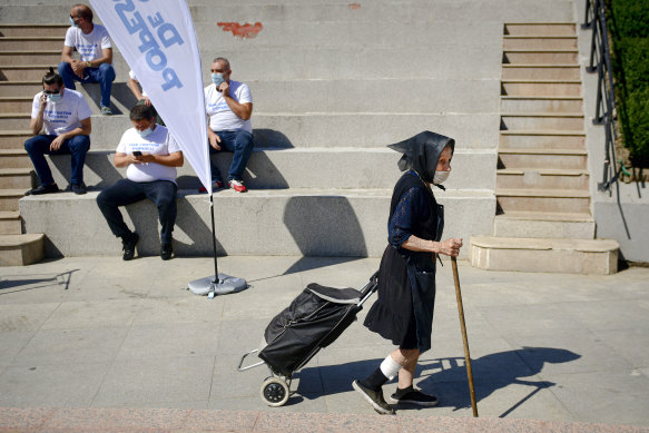 An elderly woman walks past people attending an electoral event in Bucharest, Romania. The country has been identified as the true location of a network of pro-Trump social media accounts.