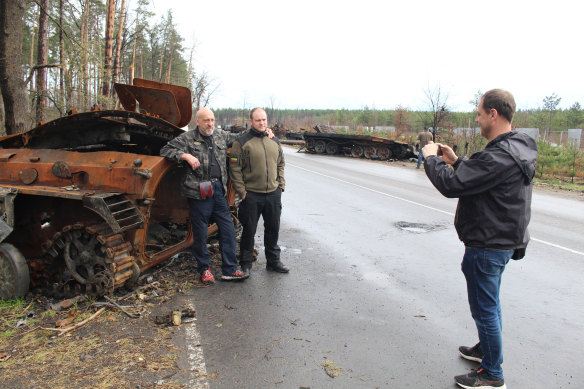 Serhii Grishin takes a photo of his friends next to a destroyed Russian armored personnel carrier in Dmytrivka, Ukraine, on April 26.
