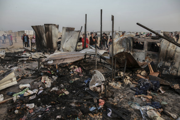 Palestinians look at the destruction after an Israeli strike where displaced people were staying in Rafah, Gaza.