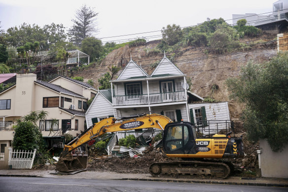 An excavator works at a home badly damaged by flooding and landslides in Auckland.
