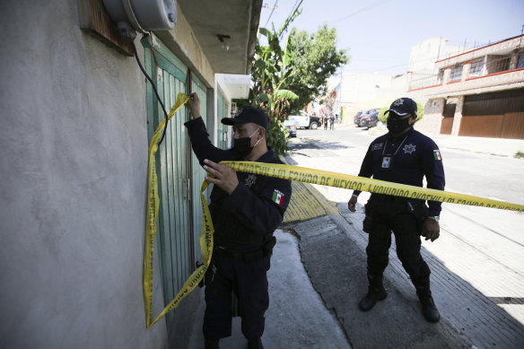 A police officer marks a security perimeter around the house where bones were found under the floor.