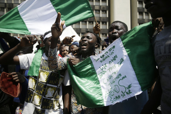 People hold banners as they demonstrate on the street to protest against police brutality, in Lagos, Nigeria.