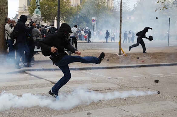A protester kicks a tear gas canister in Paris.